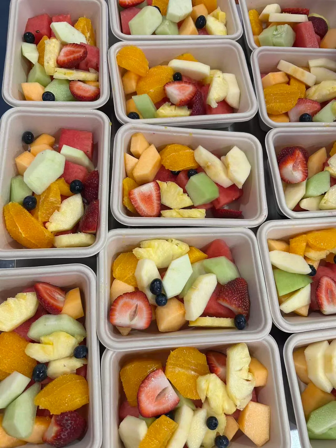 An overhead view of VC Yogurt fresh-cut fruit arranged in individual boxes.